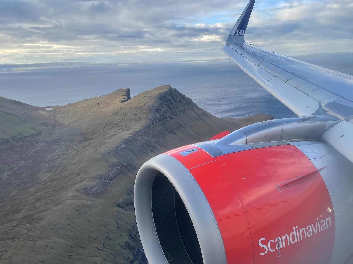 an airplane wing and engine above a mountain