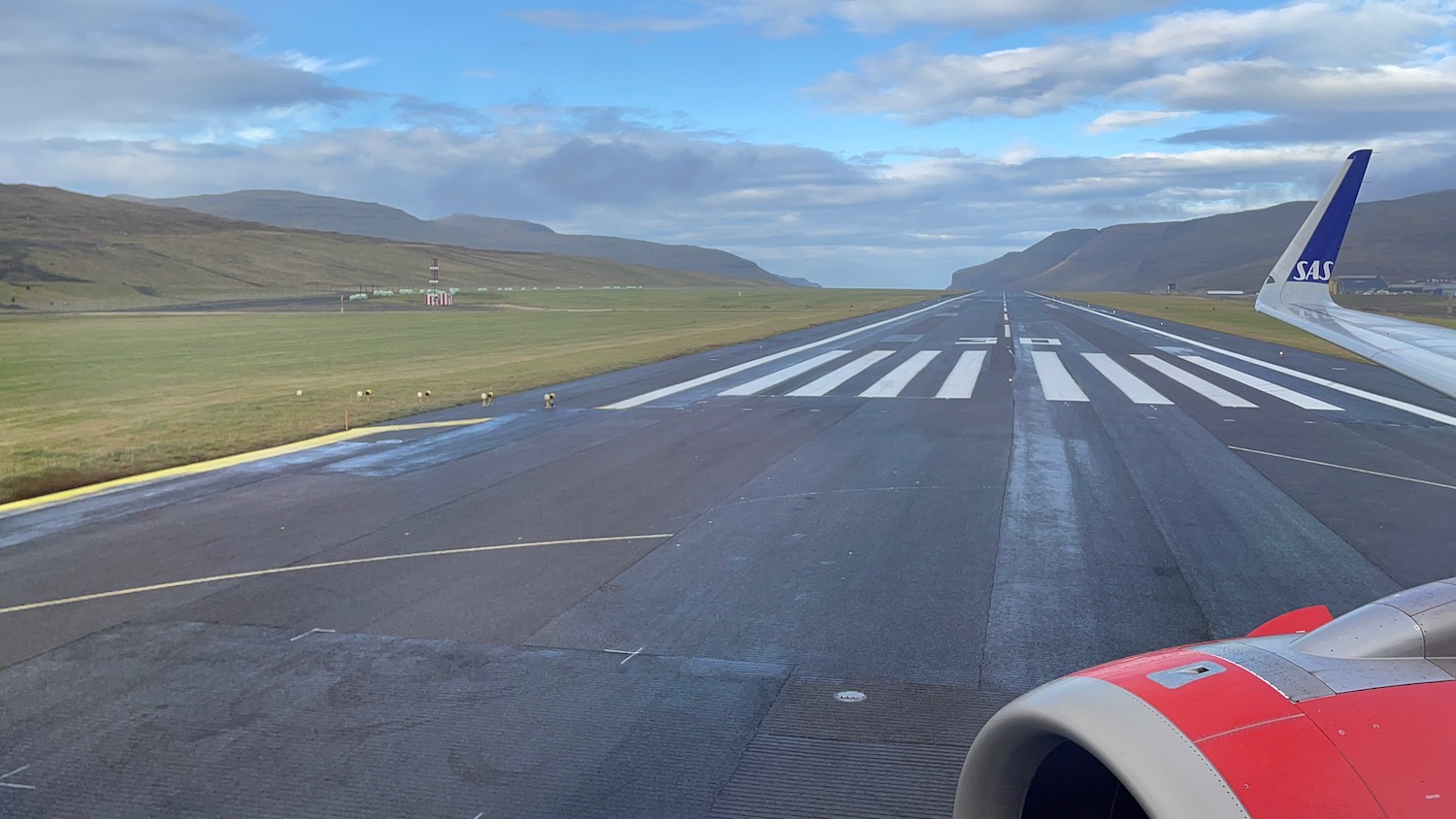 a runway with grass and mountains in the background