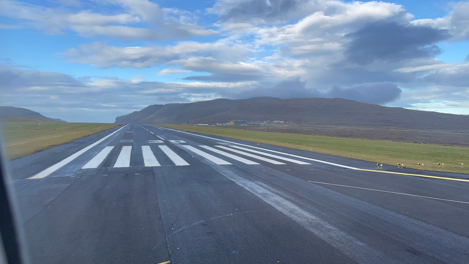 a runway with a field and hills in the background