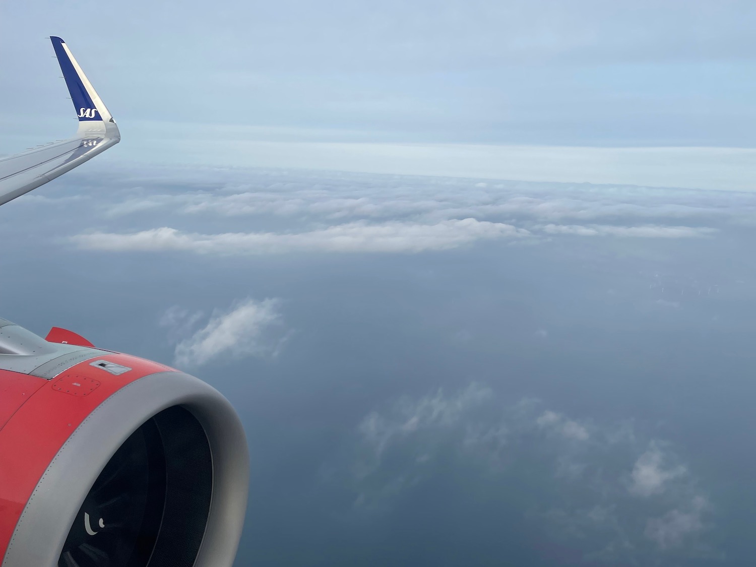 an airplane wing and engine above clouds