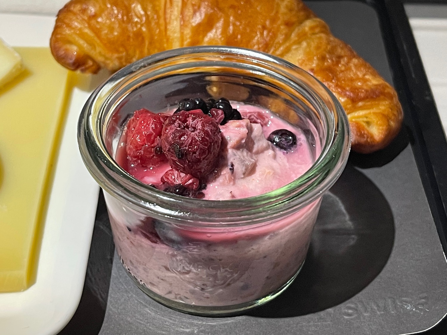 a glass jar with food in it next to a croissant