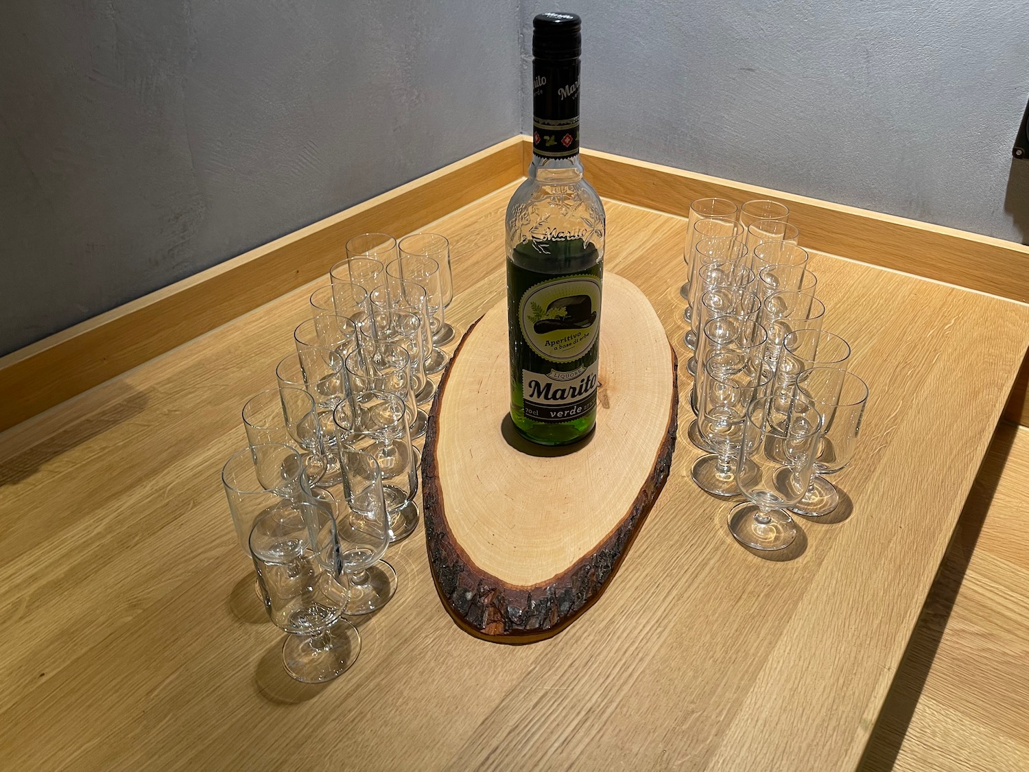 a bottle of alcohol on a wood slice with many empty glasses