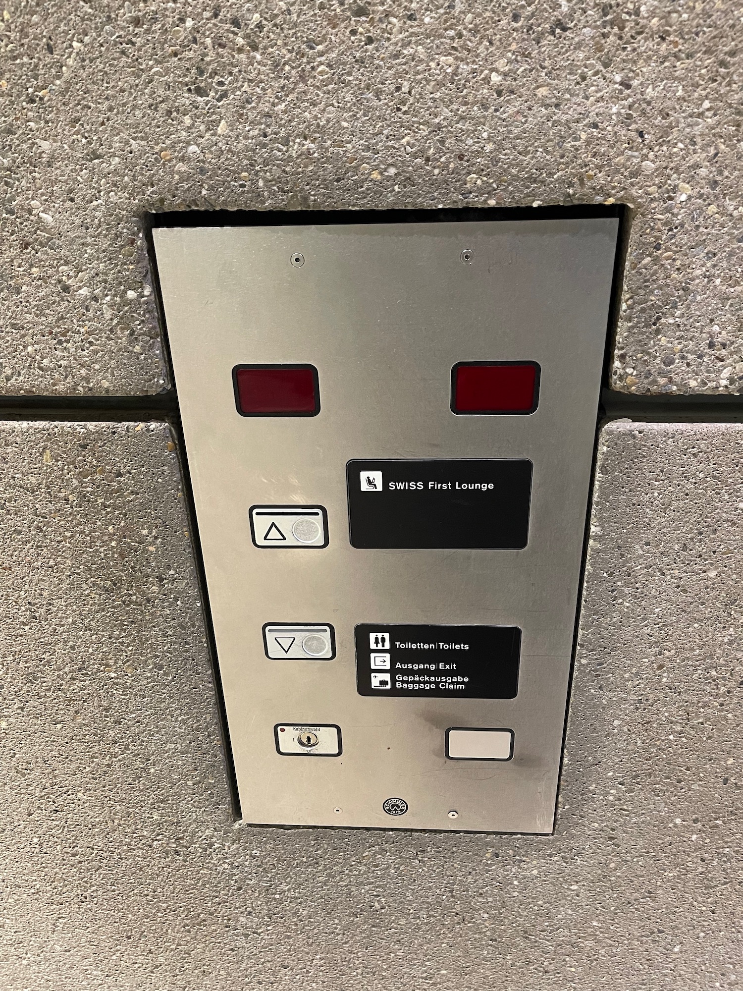 a rectangular metal panel with buttons and signs on the wall