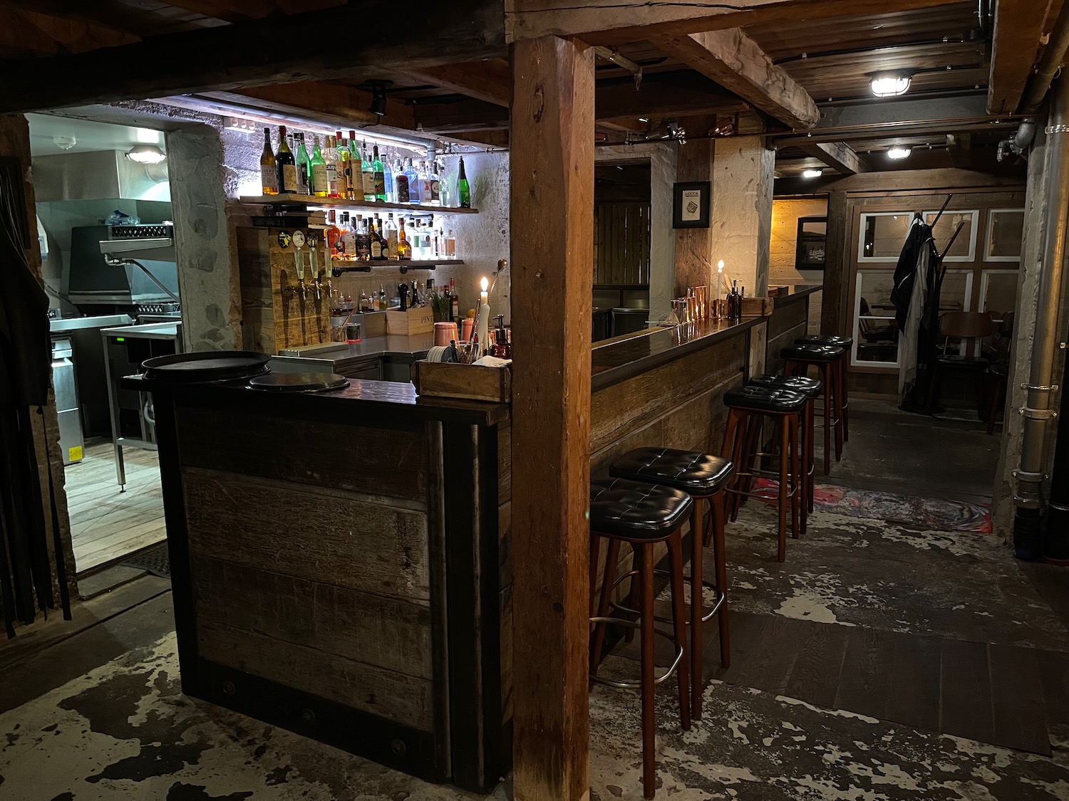 a bar with stools and bottles on the shelves