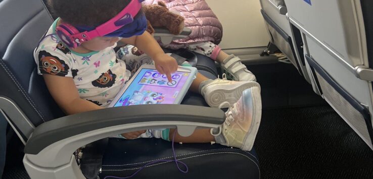 a child sitting in an airplane with a tablet