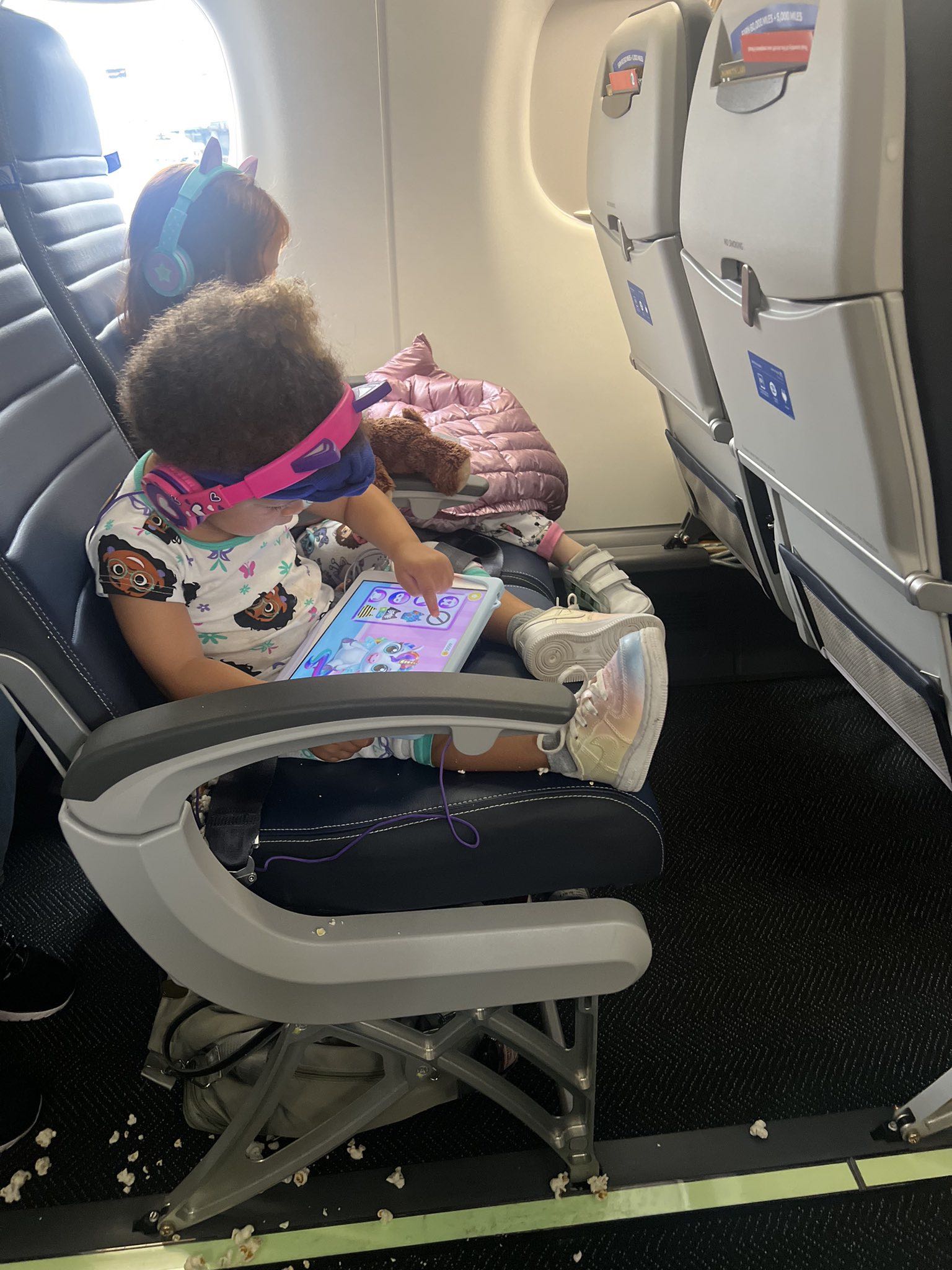 a child sitting in an airplane with a tablet