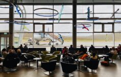 people sitting in a lounge area with a plane in the background