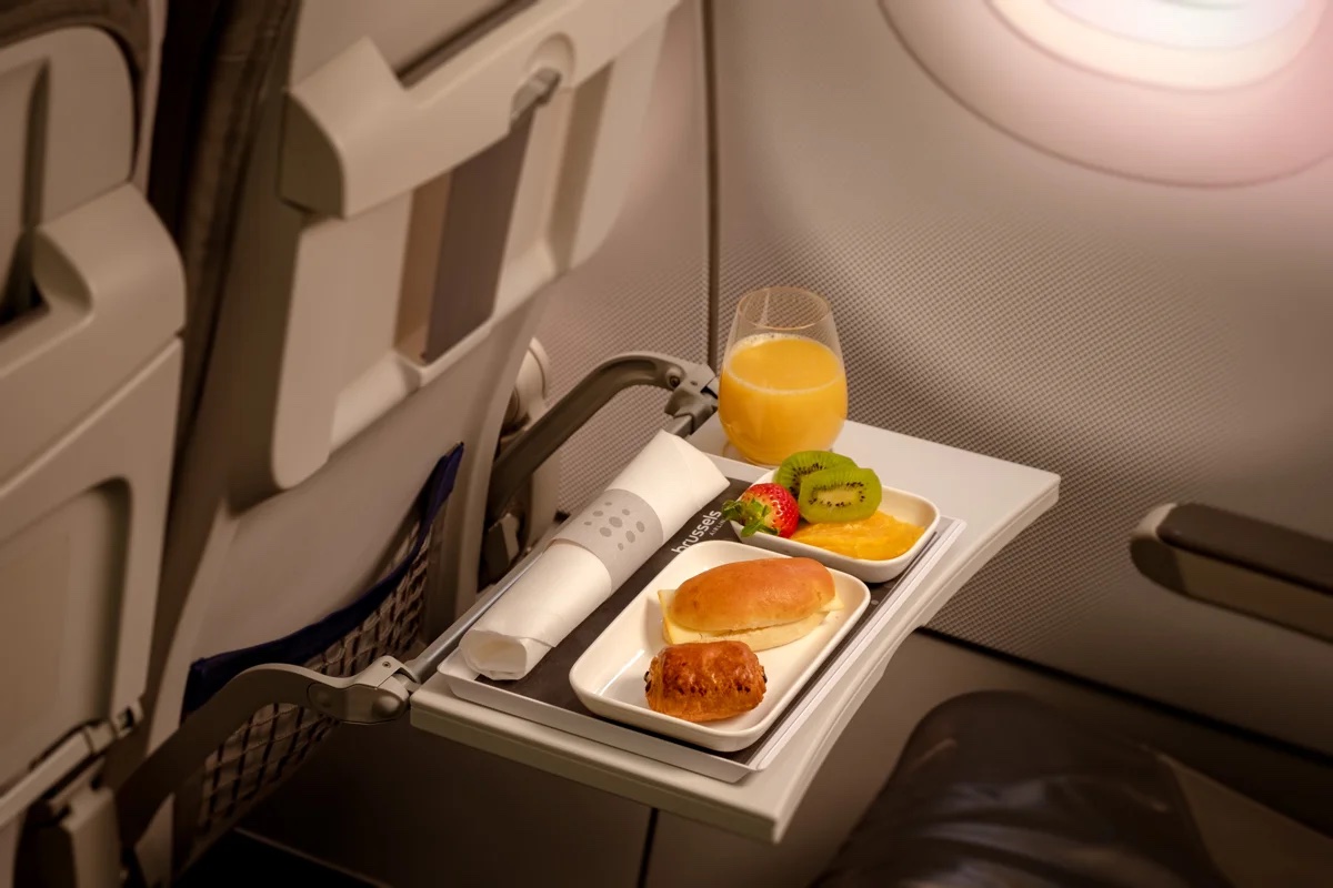 a tray of food and a glass of juice on an airplane