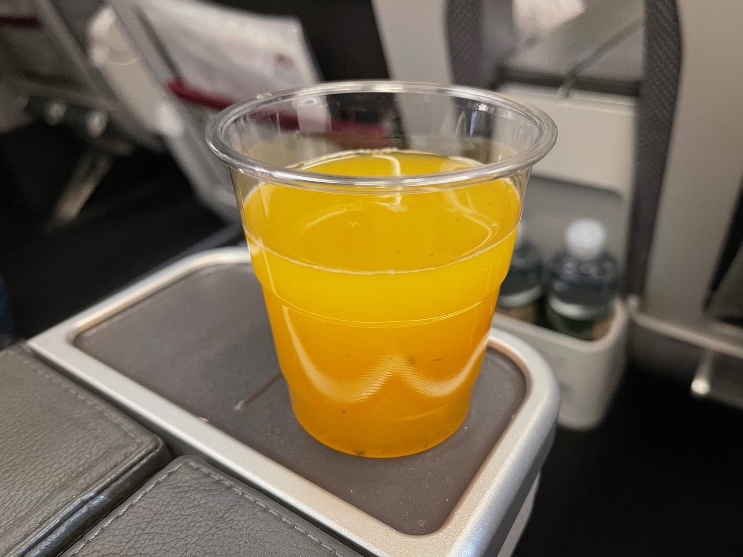 a plastic cup with orange liquid on a tray