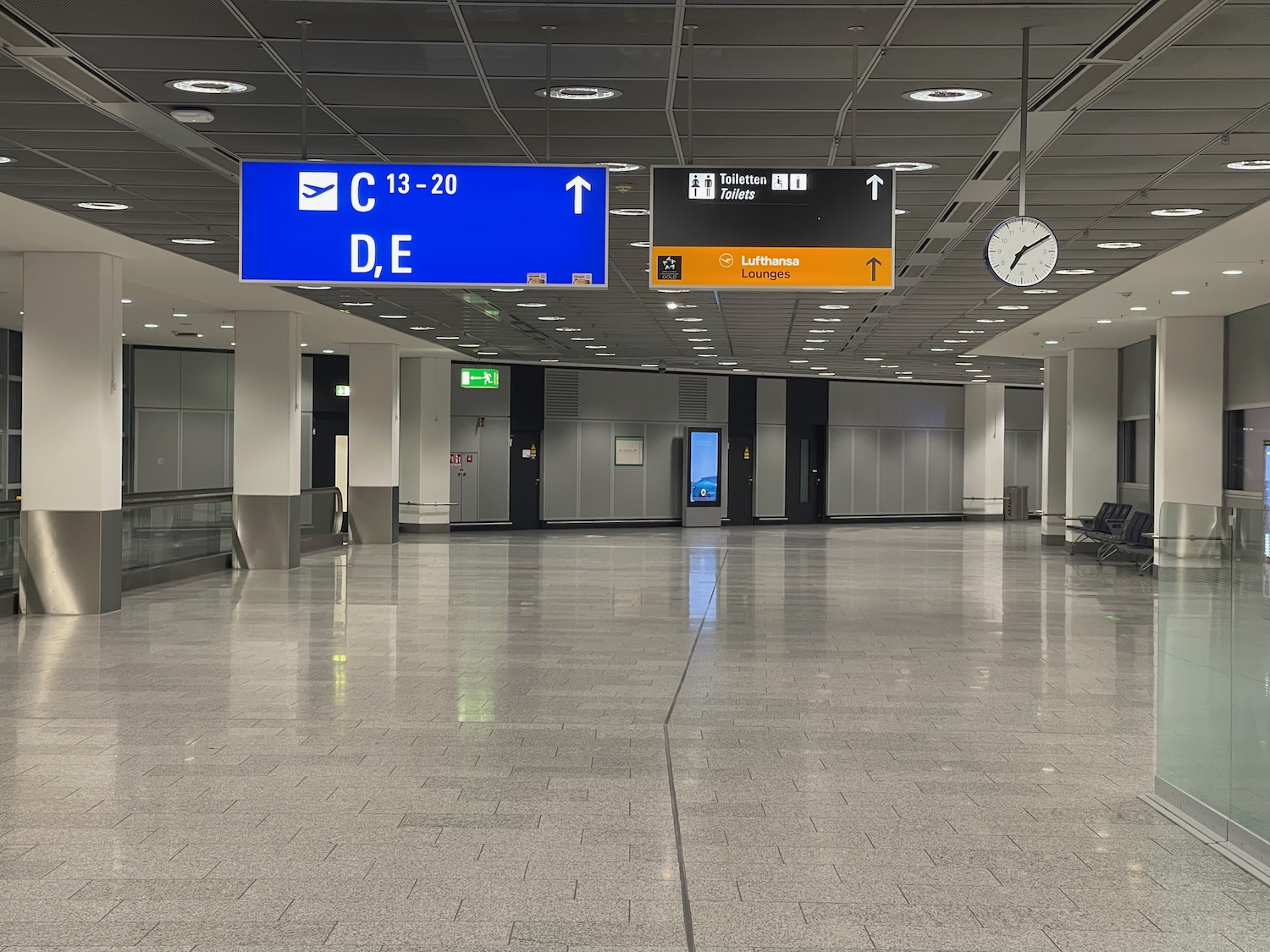 a large airport terminal with signs and chairs