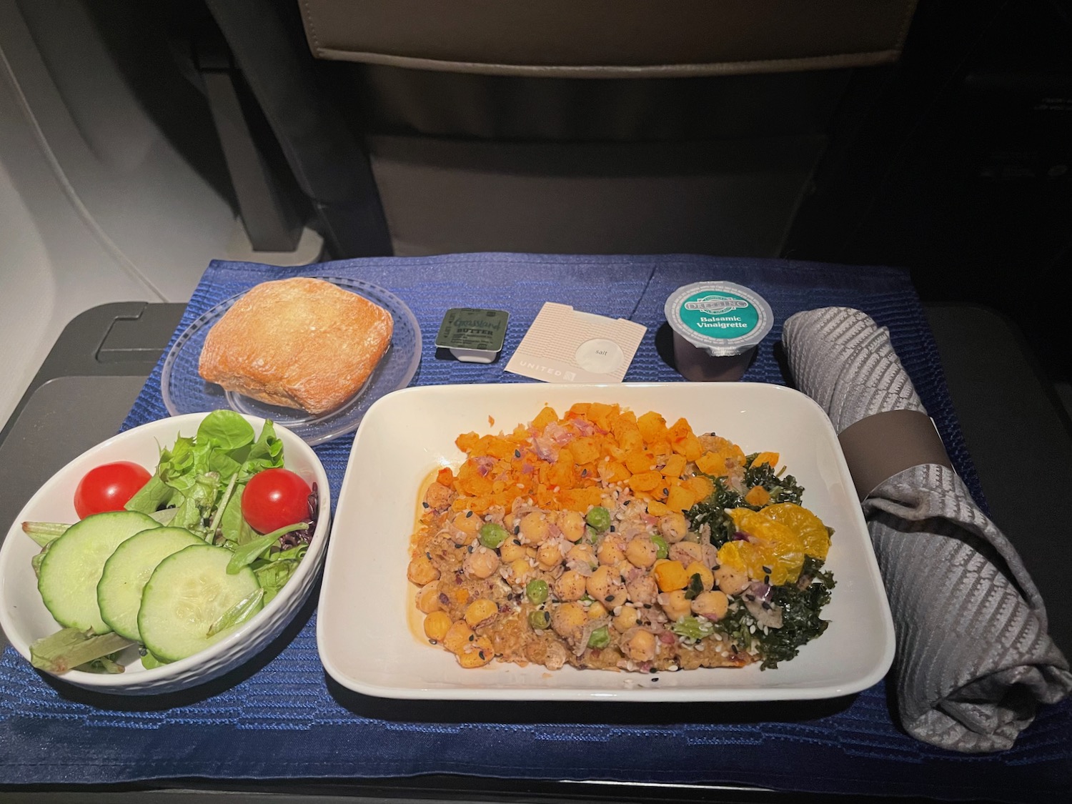 a plate of food and a bowl of bread on a blue place mat