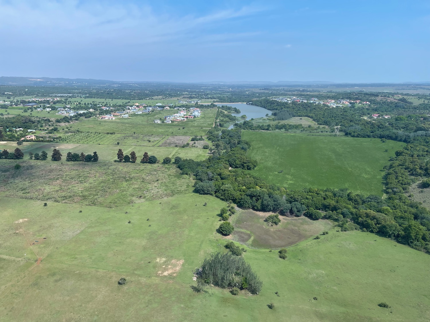 a green field with trees and a river