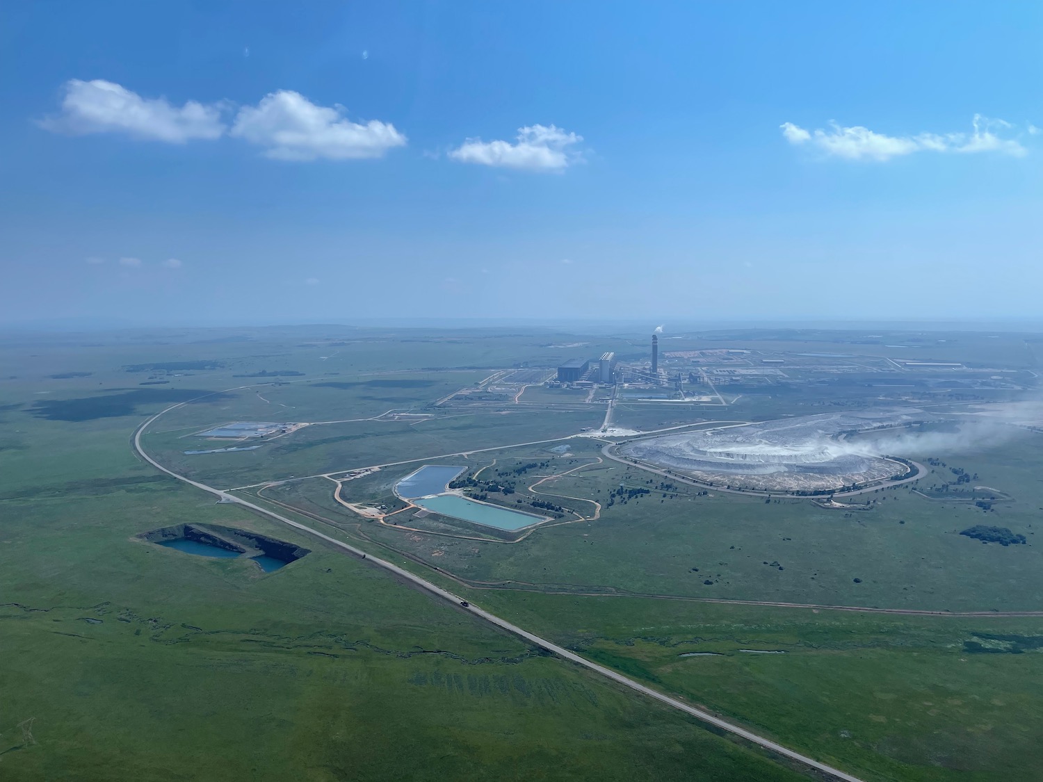 a green field with a road and a factory