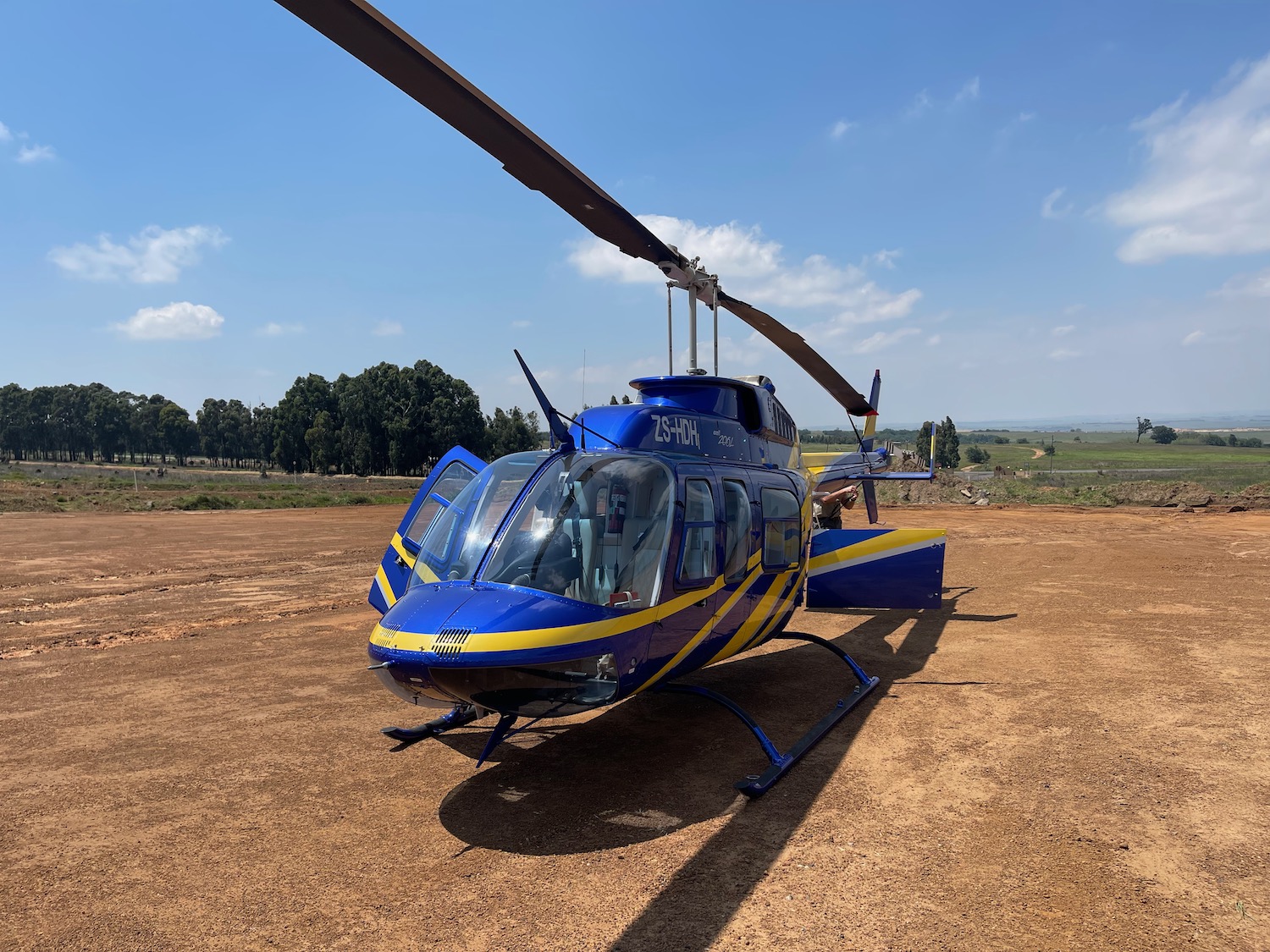 a blue and yellow helicopter on a dirt field