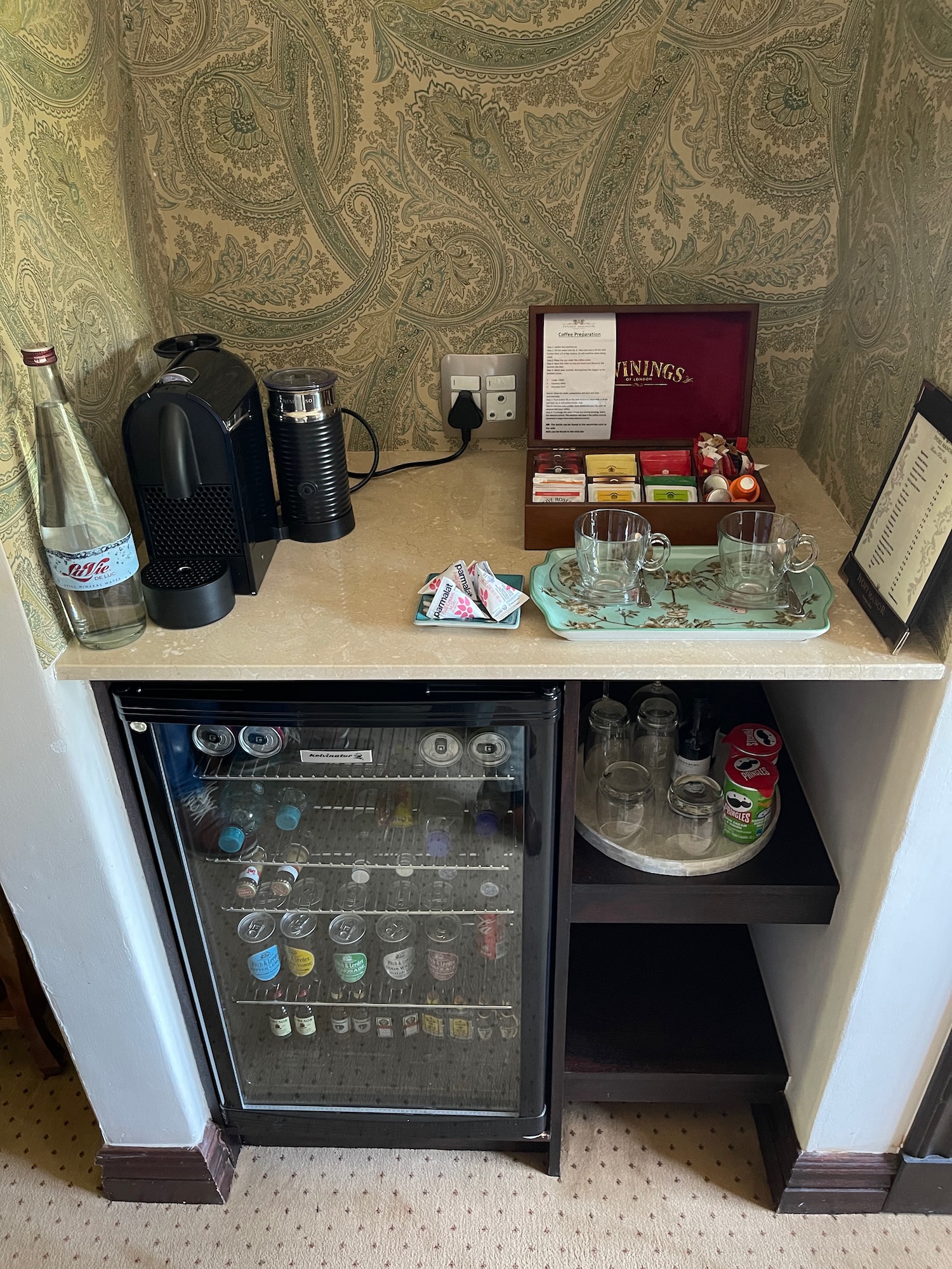 a small bar with a small fridge and a tray of glasses