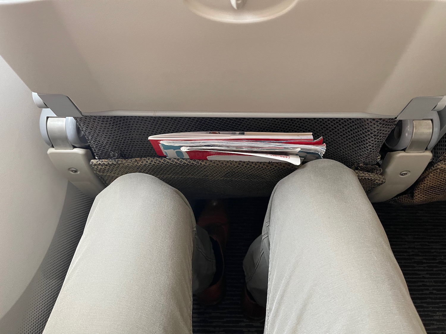 a person's legs and legs in a seat with a magazine in the back