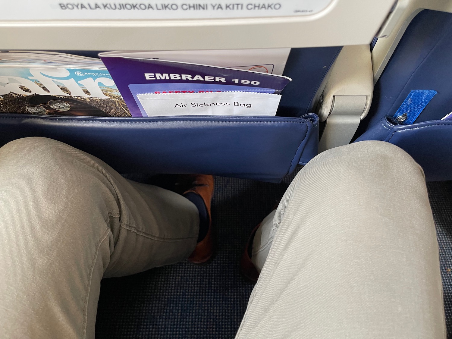 a person's legs and a magazine in the seat of an airplane