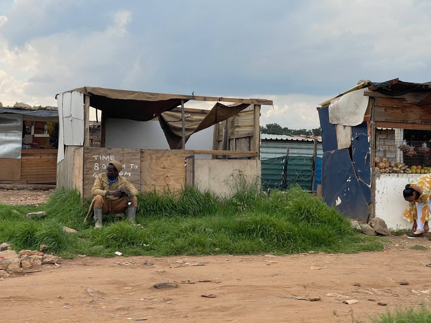 a man sitting in the grass next to a shack