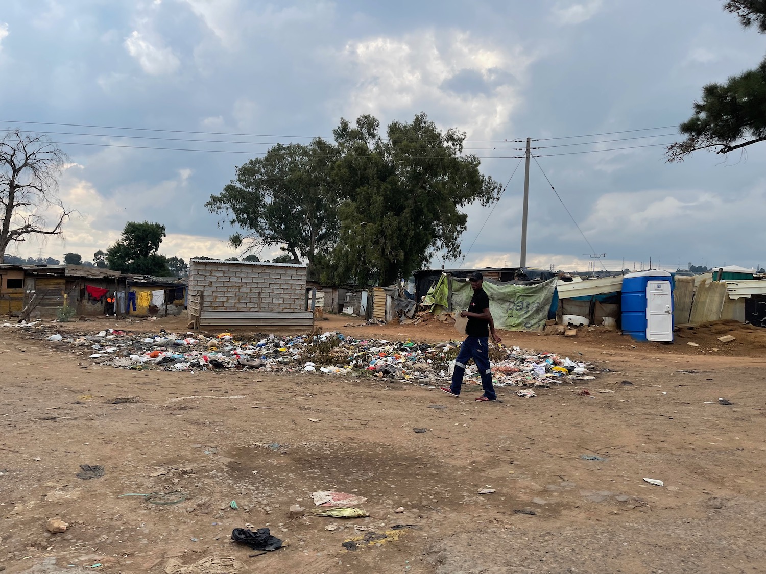 a man walking in a dirt area with garbage