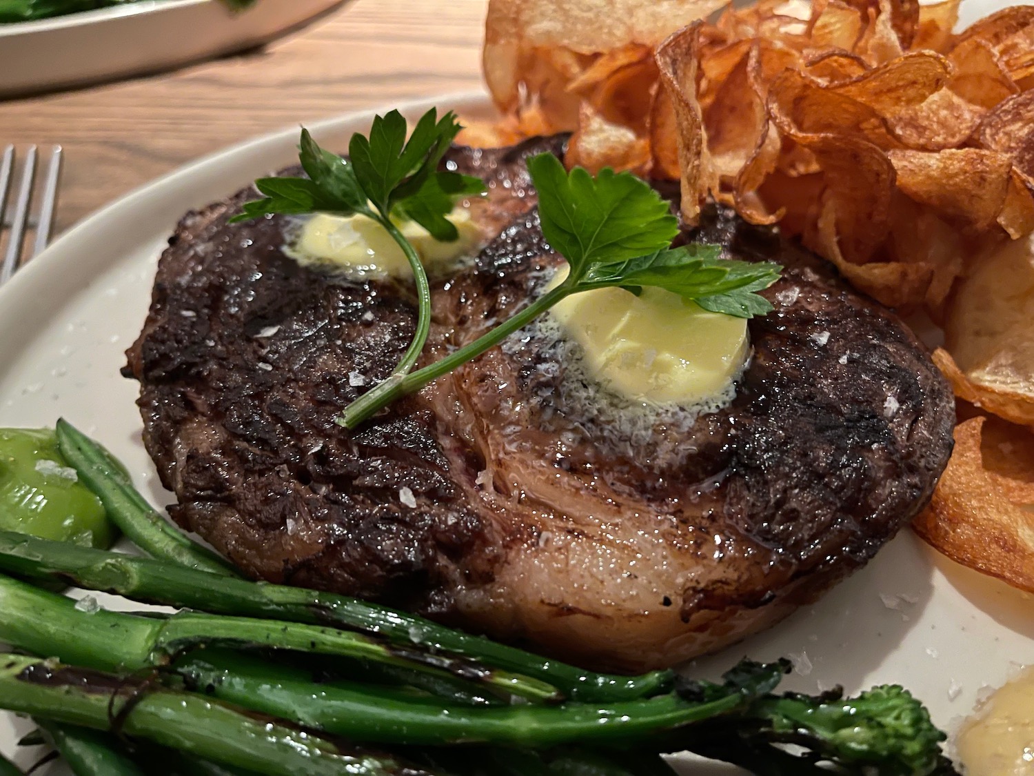 a plate of food with a piece of steak and potato chips