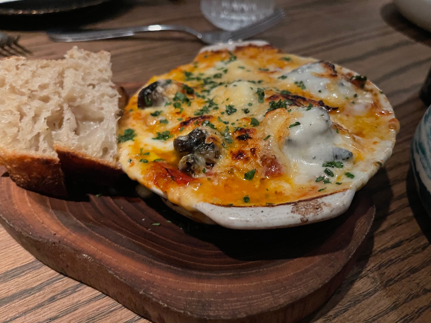 a baked mushroom with cheese and bread on a wooden board