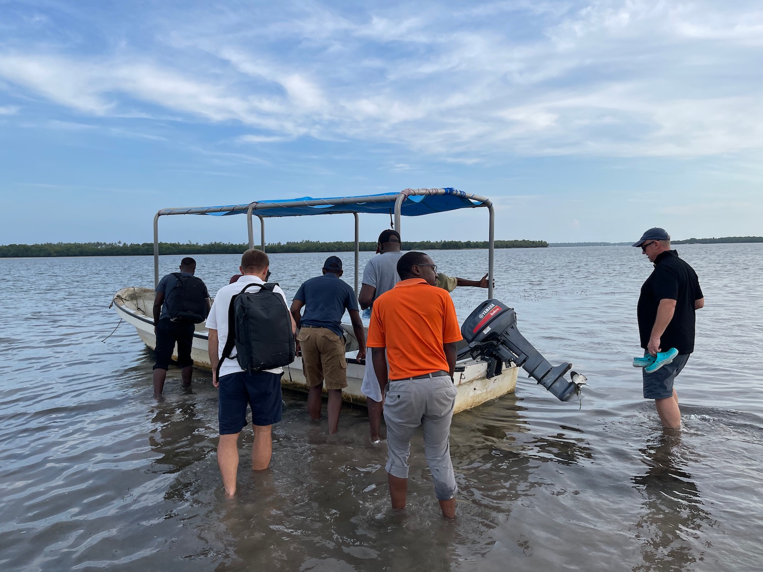 a group of people standing in water with a boat