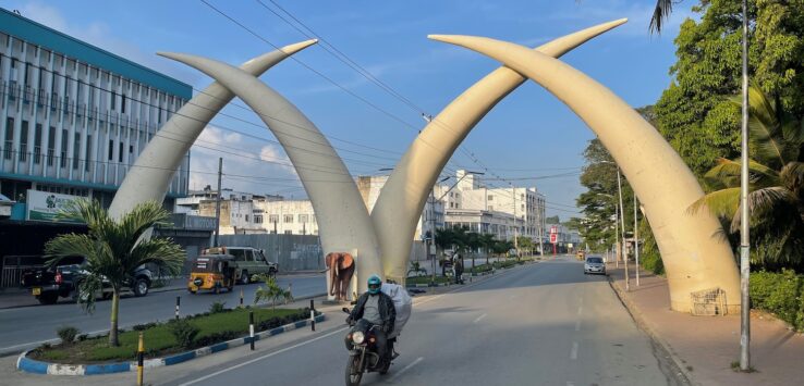 a man riding a motorcycle on a road with tusks