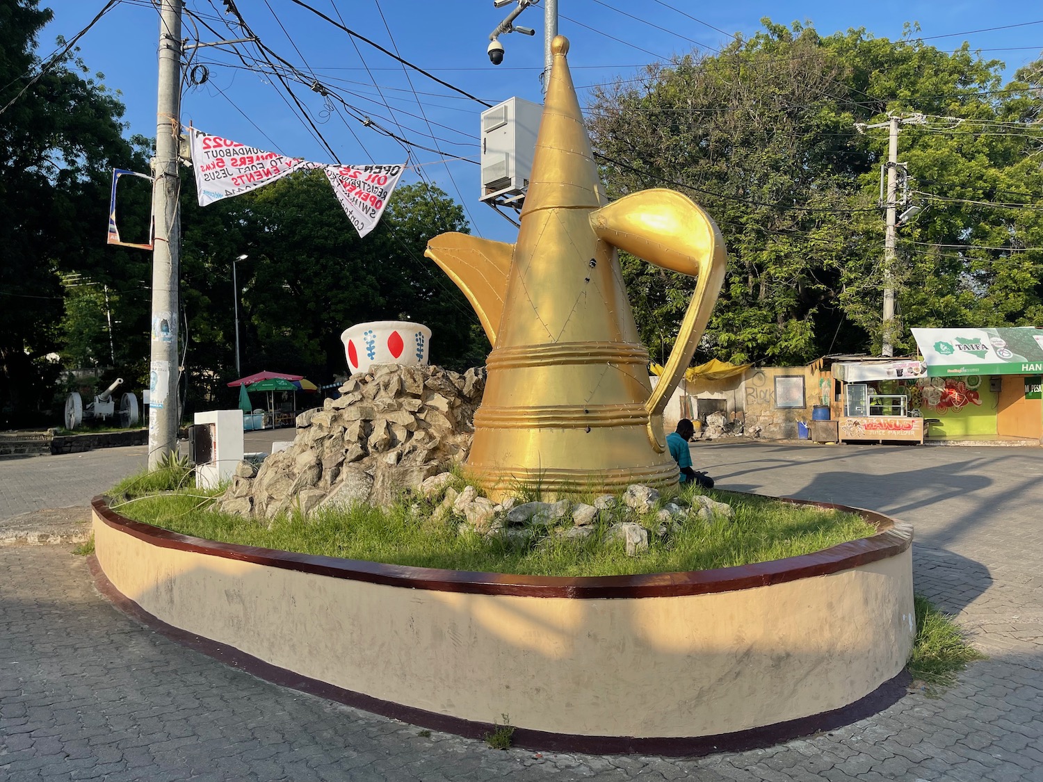 a large gold teapot statue in a circular area