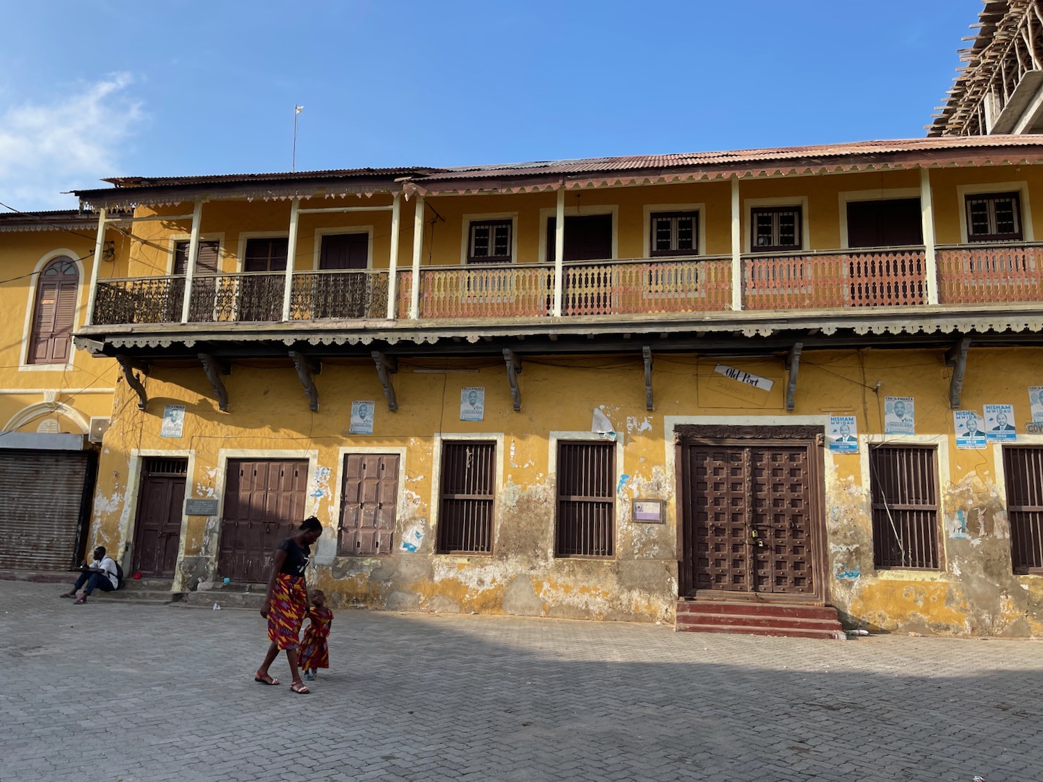 a woman and child walking in front of a yellow building