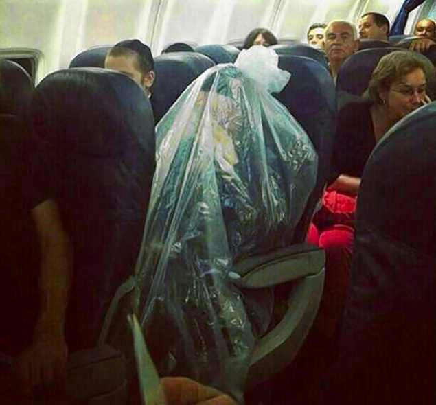 a person wrapped in plastic in a seat on an airplane