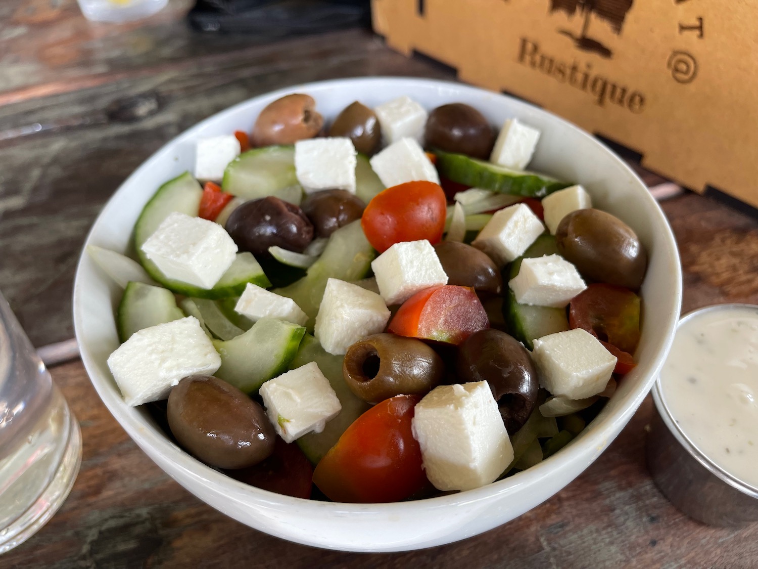 a bowl of salad with olives and cheese