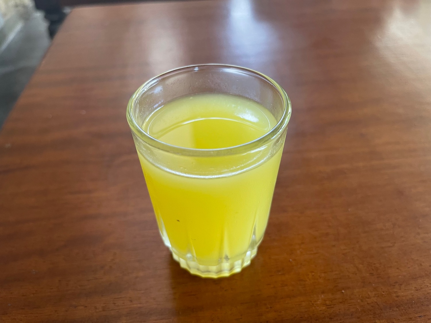 a glass of yellow liquid on a table