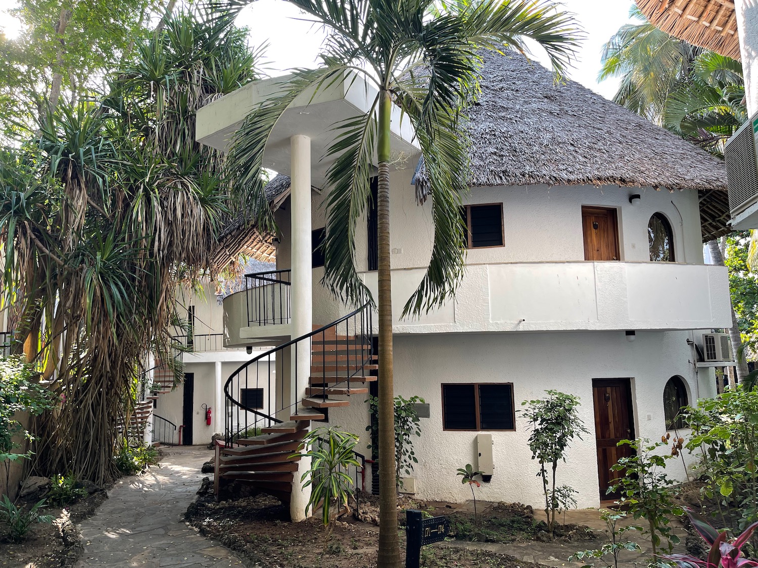 a white building with a round staircase and palm trees