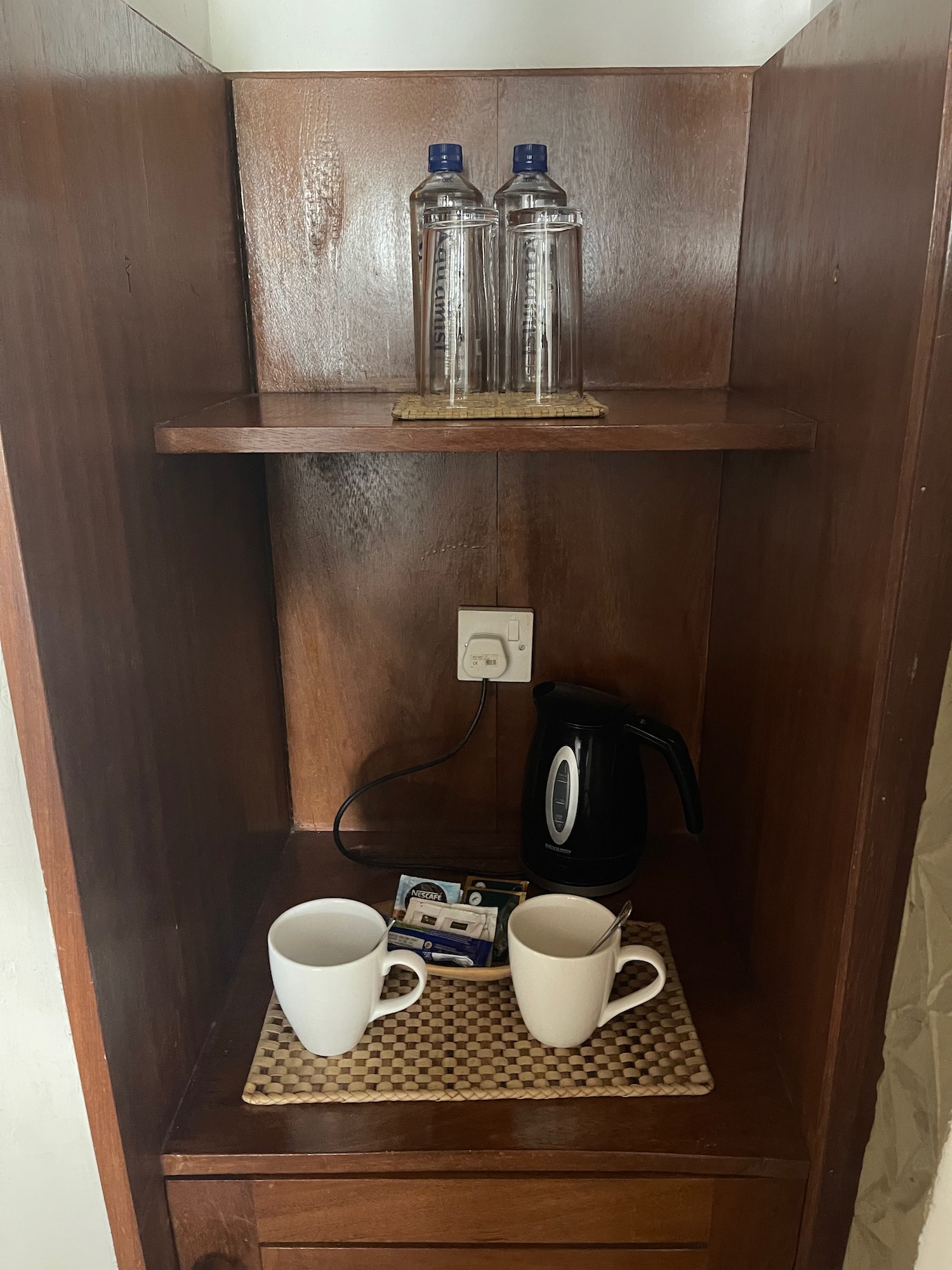 a shelf with cups and water bottles on it