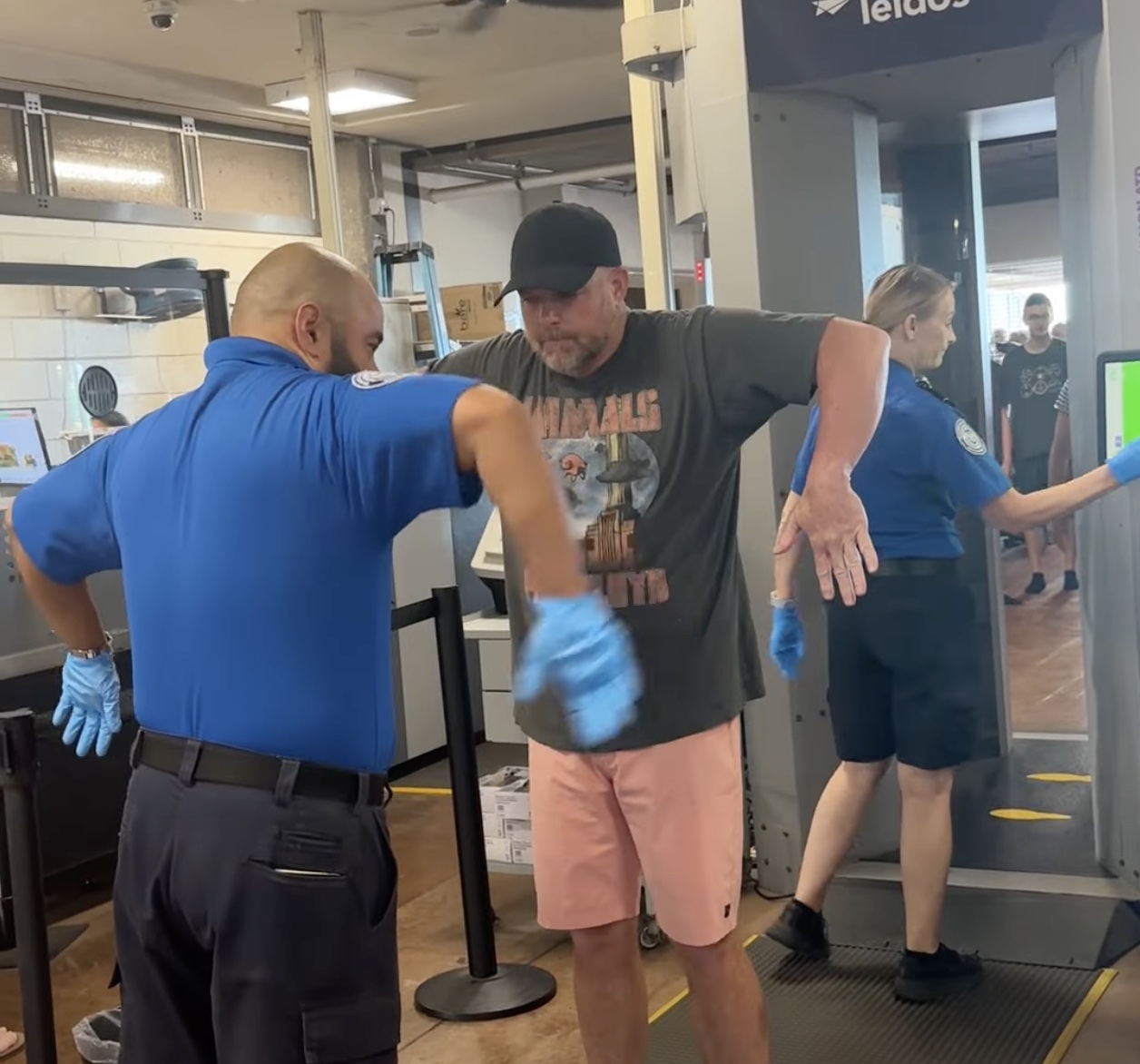 a man in a blue shirt and gloves standing next to a man in a blue shirt