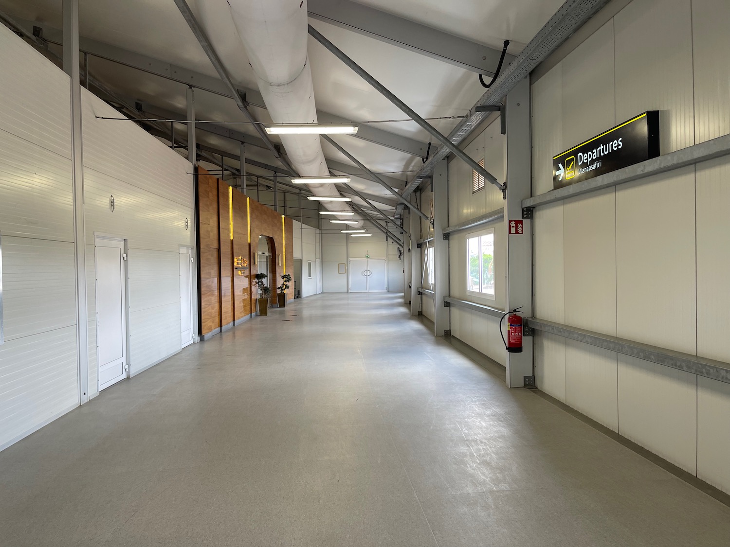 a long white hallway with metal beams and a sign