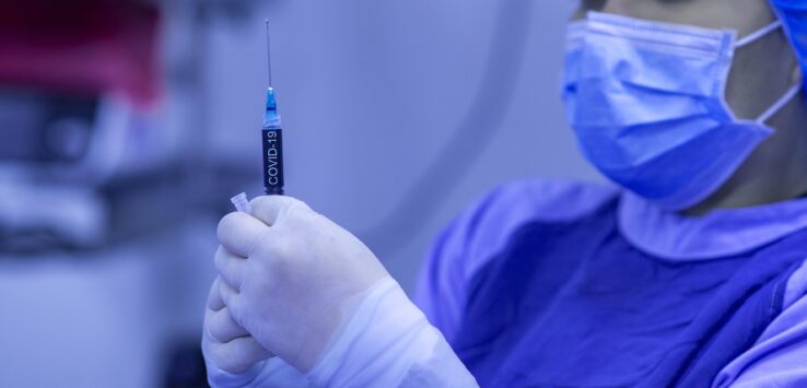 a person in a surgical mask holding a syringe