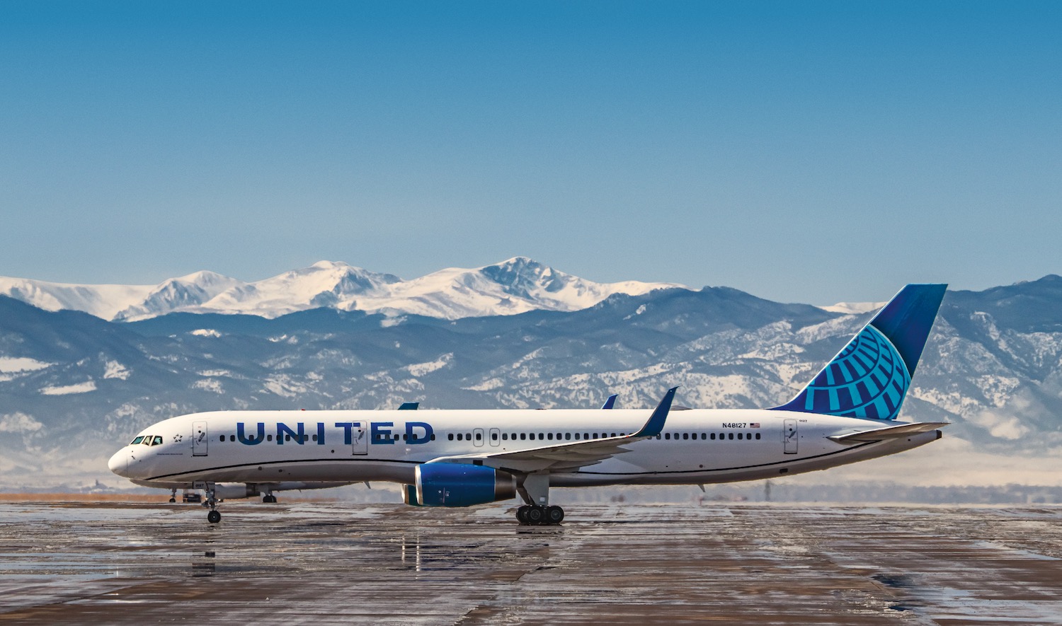 a plane on a runway with mountains in the background