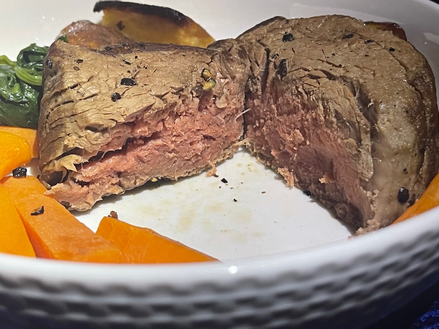 a piece of meat and vegetables in a white bowl