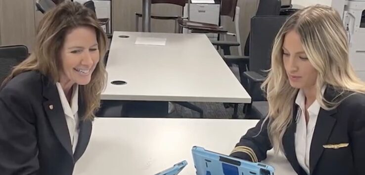 a couple of women in uniform sitting at a table looking at a tablet