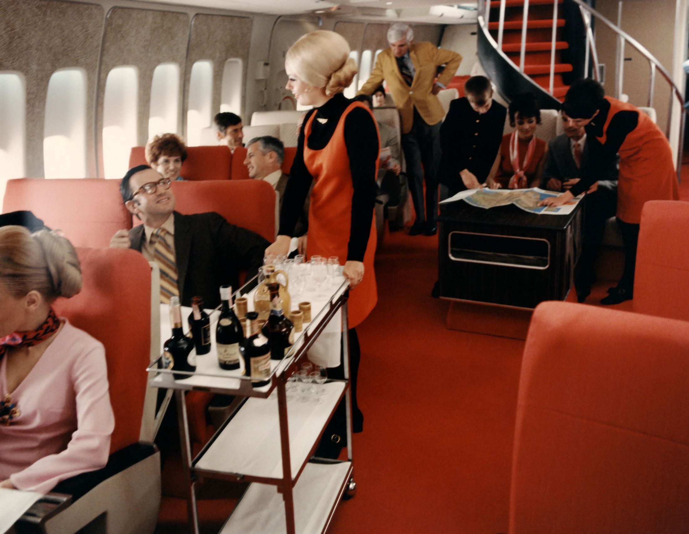 a woman serving drinks on a cart in an airplane