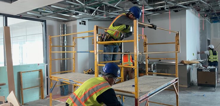 a group of men in safety vests and helmets working on a metal platform