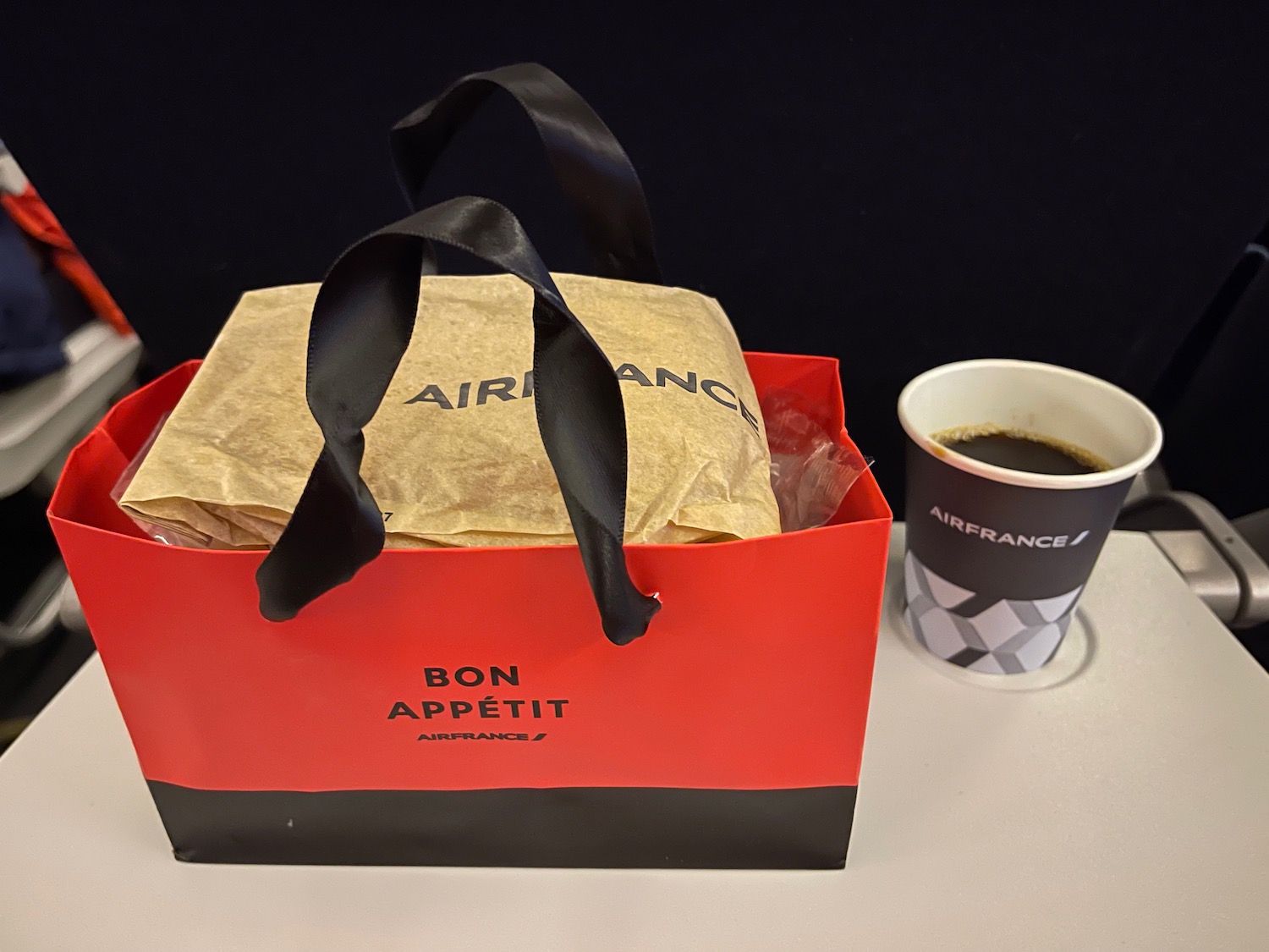a bag with a black handle next to a cup of coffee
