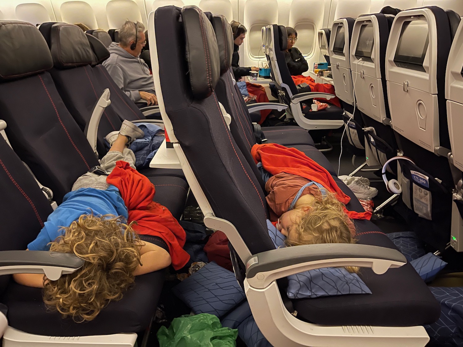 a group of people sleeping on seats in an airplane