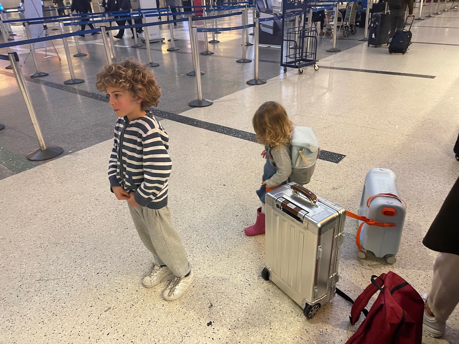 a boy and girl standing next to luggage