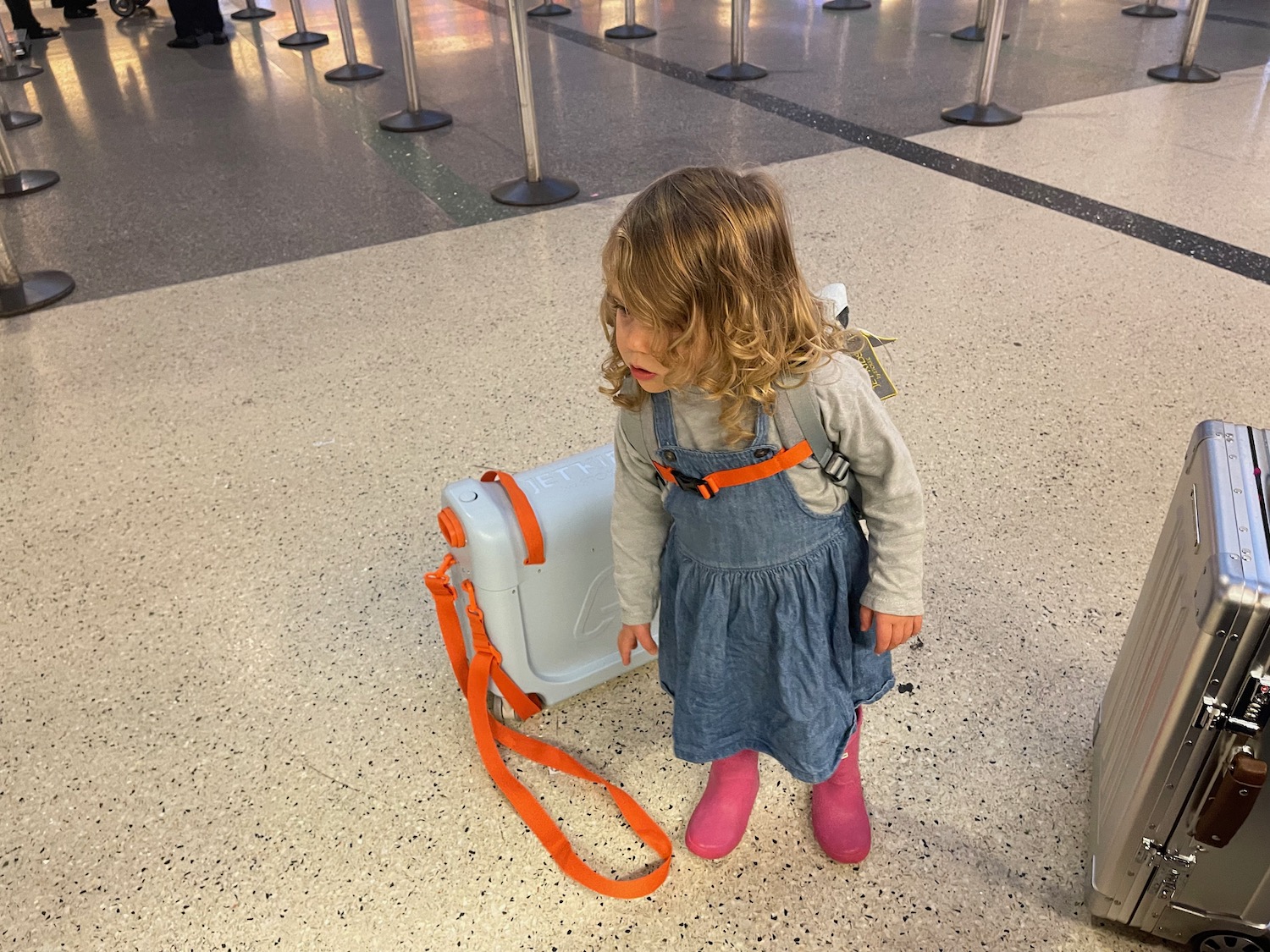 a little girl standing next to a luggage case