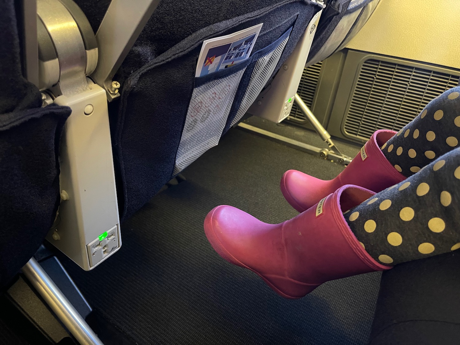 a pair of feet in pink boots on an airplane