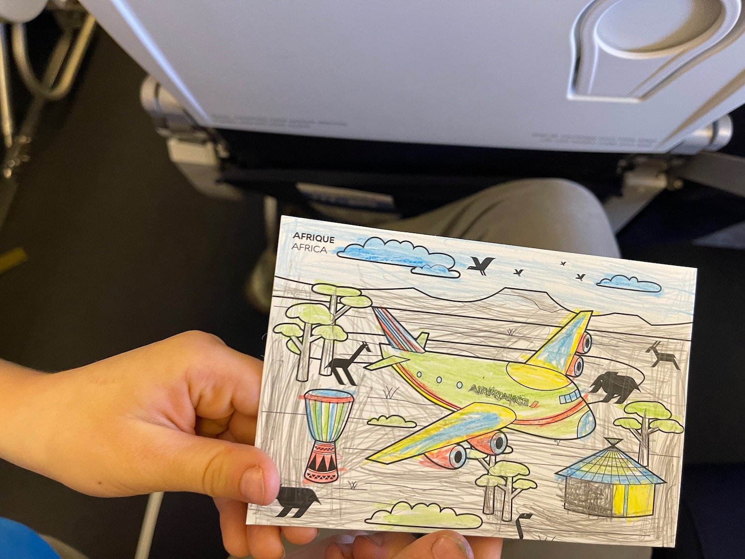 a hand holding a piece of paper with a drawing of an airplane
