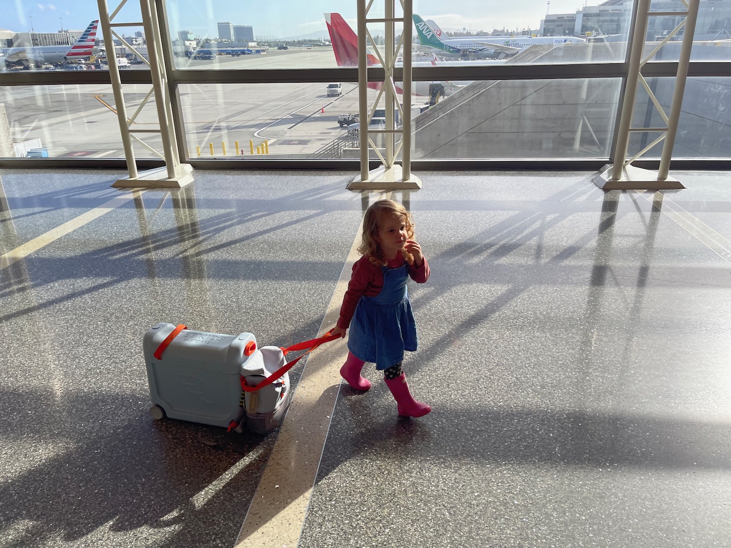 a girl walking with a suitcase in an airport