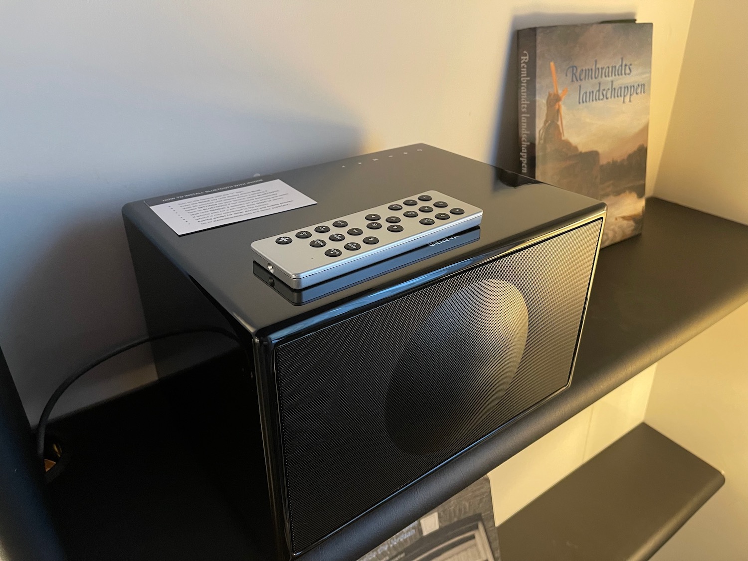 a black rectangular speaker with a remote control on top